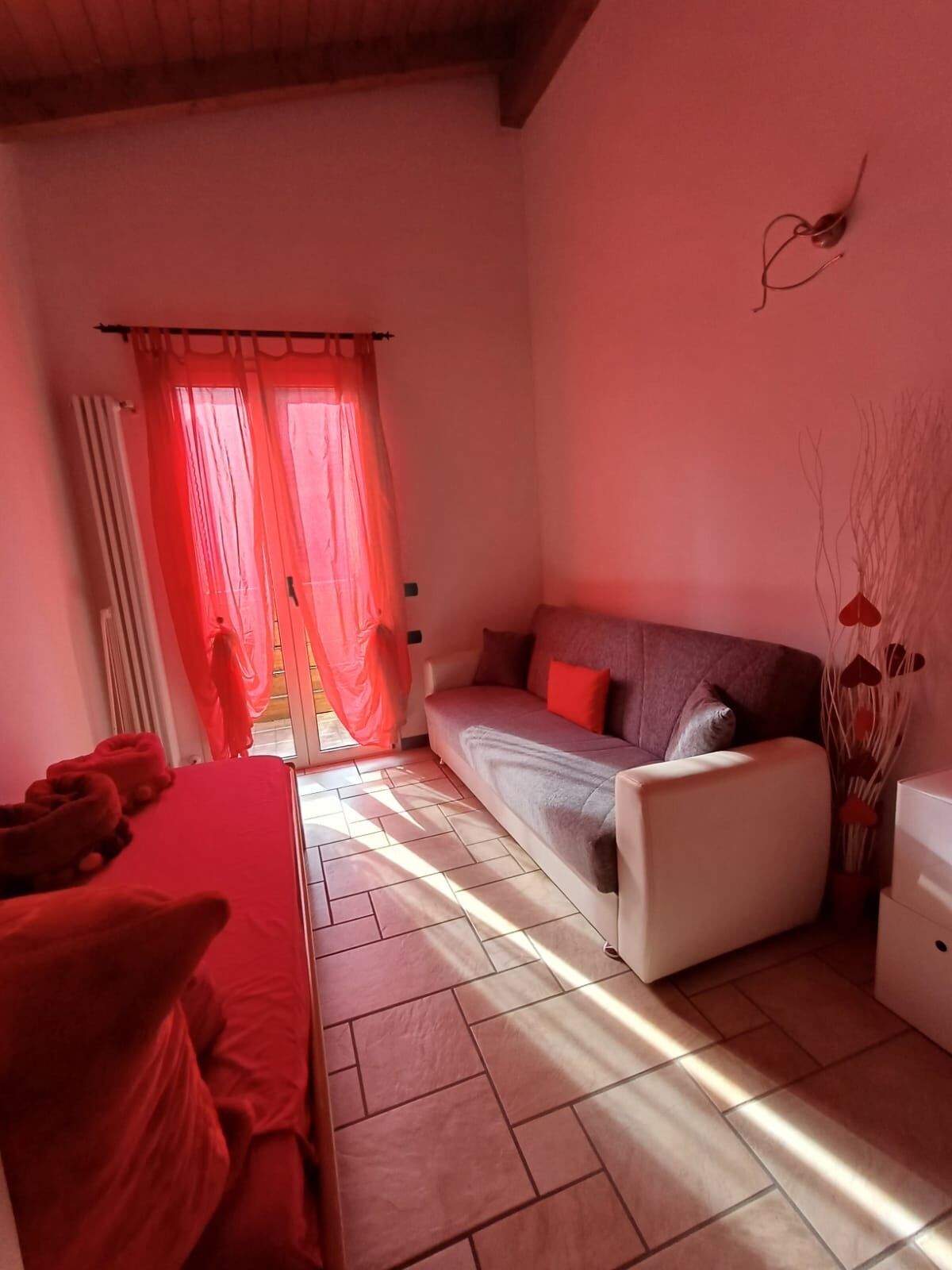 Ein Zimmer mit einer Couch, einem Bett und einem Fenster mit Vorhängen.