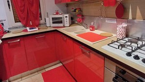 A kitchen with red cabinets, a microwave, a gas stove, and a red rug.
