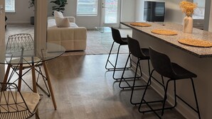 Ett modernt kök med en bardisk, ett matbord med stolar och en soffa i bakgrunden.