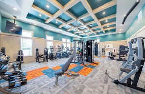 A gym with various exercise equipment, a ceiling with wooden beams, and a colorful floor.