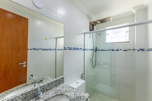A bathroom with a granite countertop, a toilet, and a glass-enclosed shower. - Aptos in Beachfront Condominium in Ilheus, BA - Cals (Ilhéus)