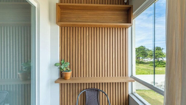 A modern interior with a vertical wooden panel wall, a potted plant, and a wicker chair.