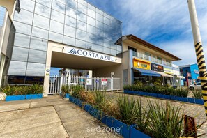 A modern building with a glass facade and a sign reading "COSTA AZUL". - Aptos in Beachfront Condominium in Ilheus, BA - Cals (Ilhéus)