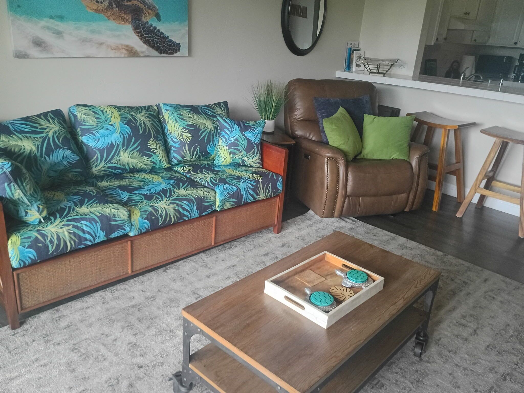 A living room with a sofa, a coffee table, a chair, and a kitchen area in the background.