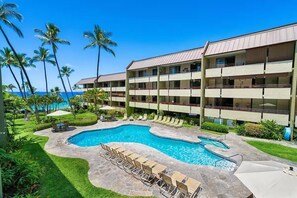 A hotel with a pool area, palm trees, and a view of the ocean. - Central AC Ocean View 2bedroom /2bath Sleeps 6 Condo across Magic Sands Beach (Kailua-Kona)