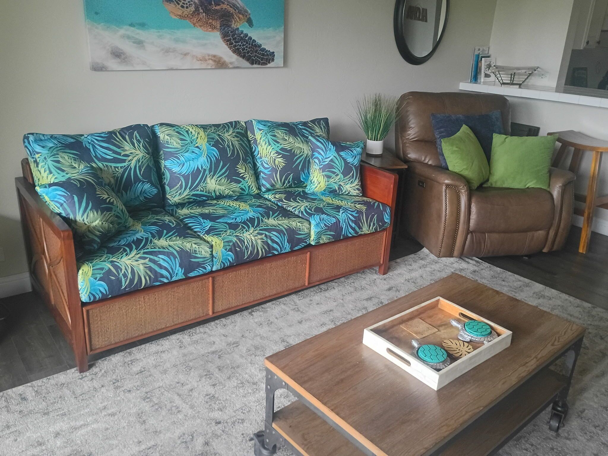 Een woonkamer met een bank, een stoel, een salontafel en een schilderij aan de muur.