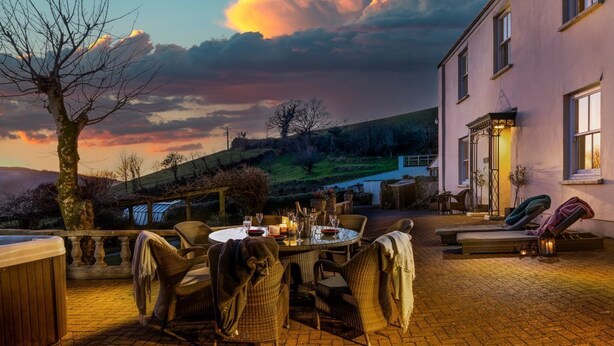 Eine Terrasse mit Korbmöbeln, einem Whirlpool und einem Esstisch.