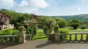 Ein gepflasterter Weg führt zu einem traditionellen Bogen mit Blick auf einen Garten.