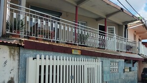 Un edifici amb un balcó, una tanca blanca i una paret blava.
