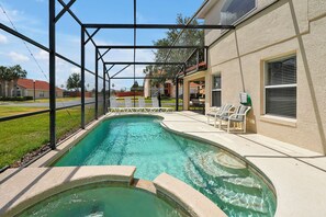 A swimming pool with a covered area, surrounded by a fence, and adjacent to a building with outdoor seating. - 5BR Private Pool Home Near Disney | FREE Pool Heat | Gated Resort (Davenport)