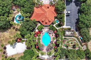 An aerial view of a resort with a central swimming pool, multiple smaller pools, and lush landscaping. - 5BR Private Pool Home Near Disney | FREE Pool Heat | Gated Resort (Davenport)
