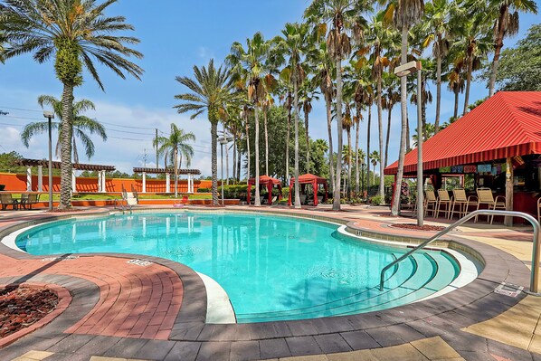A swimming pool with a red-roofed pavilion, surrounded by palm trees and a brick walkway. - 5BR Private Pool Home Near Disney | FREE Pool Heat | Gated Resort (Davenport)
