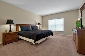 A bedroom with a bed, nightstands, a dresser, and a window with blinds. - 5BR Private Pool Home Near Disney | FREE Pool Heat | Gated Resort (Davenport)