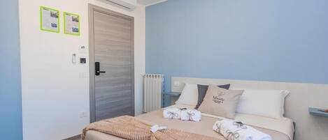 A bedroom with a bed, a radiator, a door, and two framed notices on the wall.