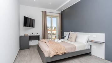 A modern bedroom with a bed, a desk, and a TV.