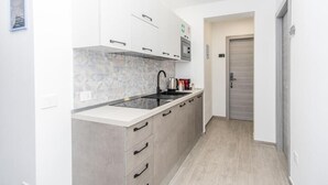 Une cuisine moderne avec des meubles blancs, un plan de travail noir et un pare-feu en carreaux.