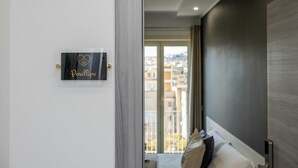 Une chambre d’hôtel avec vue sur la ville, un lit avec des oreillers, une table de chevet et un panneau accroché au mur.