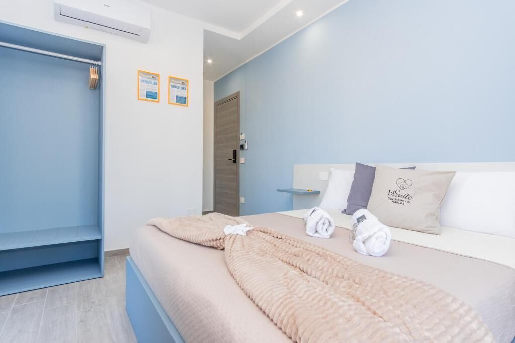 A hotel room with a bed, a blue wardrobe, and a door leading to another room.