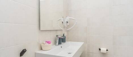 Een moderne badkamer met een witte wasbak, een spiegel en een douchekop.