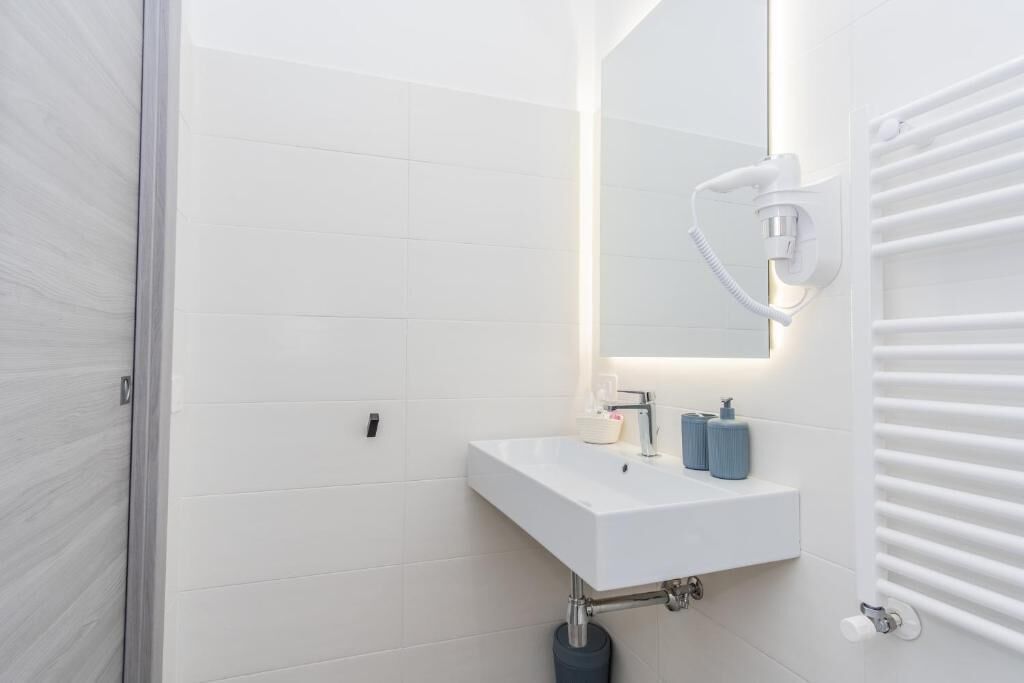 Un bagno moderno con lavandino, specchio e porta asciugamani bianchi.