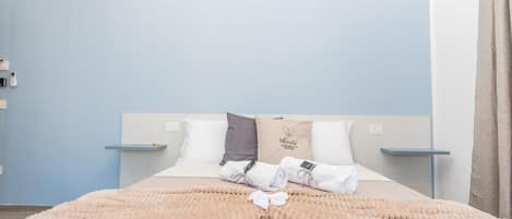 Una habitación de hotel con una cama, almohadas, una colcha y un cartel en la cabecera.