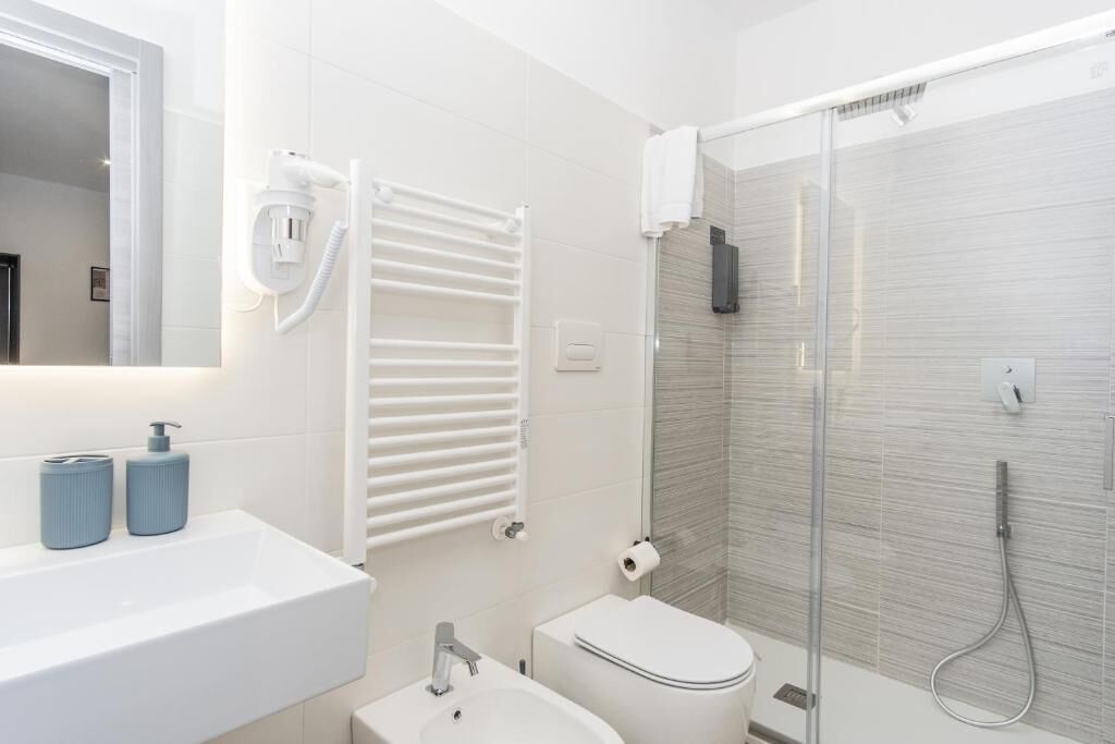 Une salle de bain moderne avec un lavabo blanc, des toilettes et une douche à parois de verre.