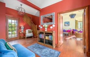 A spacious living room with a staircase, a bookshelf, and a large mirror.