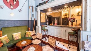 A cozy bar area with a green sofa, patterned chairs, and a wooden bar counter. - Argyll Country House (Clachan)