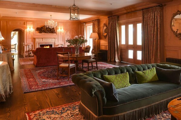A spacious living room with a green sofa, a fireplace, and a dining area.