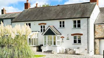 A traditional white building with a stone facade, a stone driveway, and a well-maintained lawn.