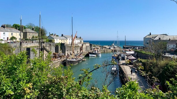 A harbor with boats, a stone wall, and buildings along the water.
