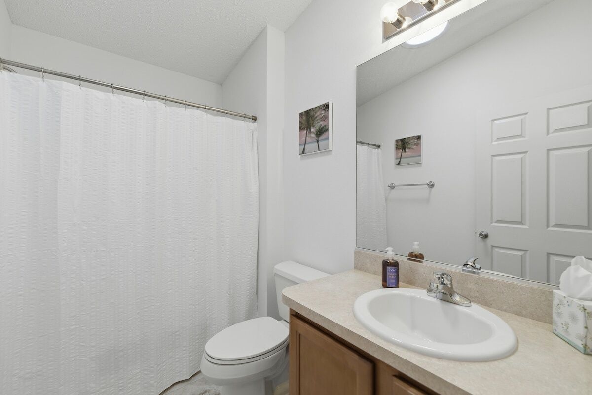 A bathroom with a toilet, sink, and shower curtain.