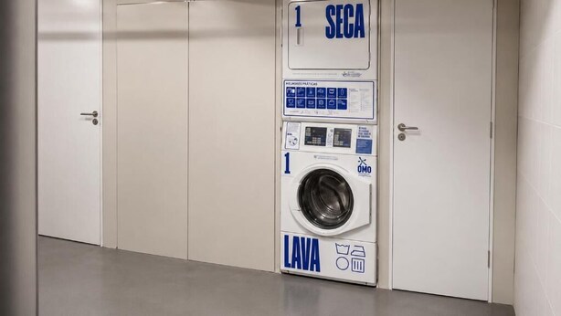 A public laundromat with a front-loading washing machine, a drying machine, and a door marked 'SECA'.