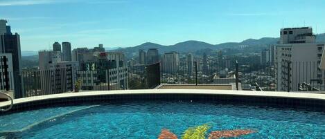 A rooftop swimming pool with a cityscape view.