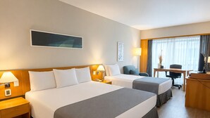 A hotel room with two beds, a desk, and a chair.