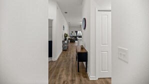 A hallway with a wooden floor, white walls, and a door on the right. - Cozy 2BR Near Eastport Sq. & Middleton | Patio (Sumterville)