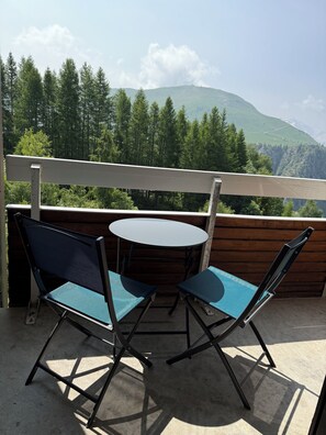 A balcony with a table and two chairs, overlooking a forested mountain range. - 150 m from the lifts - Apartment T2 for 5 people - La Marmotte en Folie (Huez)