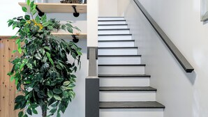 A staircase with dark steps and a handrail, leading to a landing with a shelf holding decorative items. - Private Updated Home W/ Dedicated Work Space - Close to Downtown (Chattanooga)