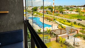 A view from a hotel room with a pool, outdoor seating, and a tall communication tower in the background.