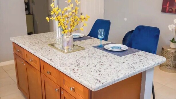 Een moderne keuken met een granieten aanrecht, houten kastjes en een centraal eiland.