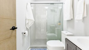 Ein kleines Badezimmer mit Duschkabine aus Glas, Toilette und Waschbecken.