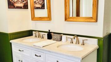 A bathroom with two sinks, a large mirror, and a painting of flowers on the wall.