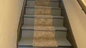 Una escalera con una alfombra texturizada que recorre el centro.
