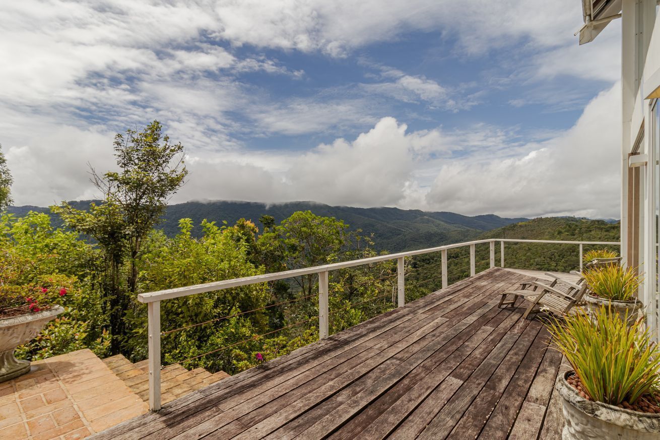 A wooden deck with a railing, overlooking a mountainous landscape.
