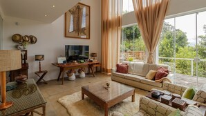 A spacious living room with a large window, a television, and a sofa. - Casa Urus Alto Padr o c Piscina Lareira e Vista (Campos do Jordão)