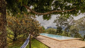 A swimming pool with a stone deck, surrounded by lush greenery and a hammock. - Casa Urus Alto Padr o c Piscina Lareira e Vista (Campos do Jordão)