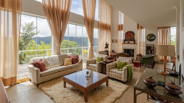 A spacious living room with a large window, a fireplace, and a cozy seating area. - Casa Urus Alto Padr o c Piscina Lareira e Vista (Campos do Jordão)