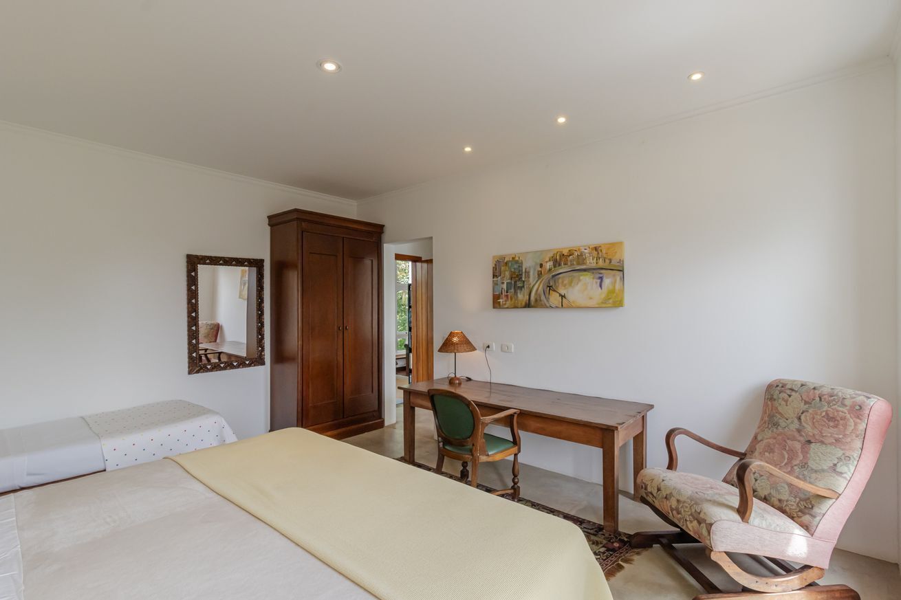 Ein Schlafzimmer mit Bett, Schreibtisch, Stuhl, Spiegel und einem Gemälde an der Wand.