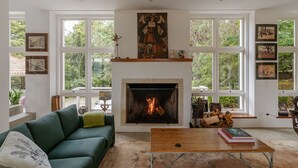 A living room with a fireplace, green sofa, wooden coffee table, and large windows. - Casa Urus Alto Padr o c Piscina Lareira e Vista (Campos do Jordão)