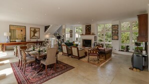 A spacious living room with a fireplace, dining area, and a staircase leading to an upper floor. - Casa Urus Alto Padr o c Piscina Lareira e Vista (Campos do Jordão)